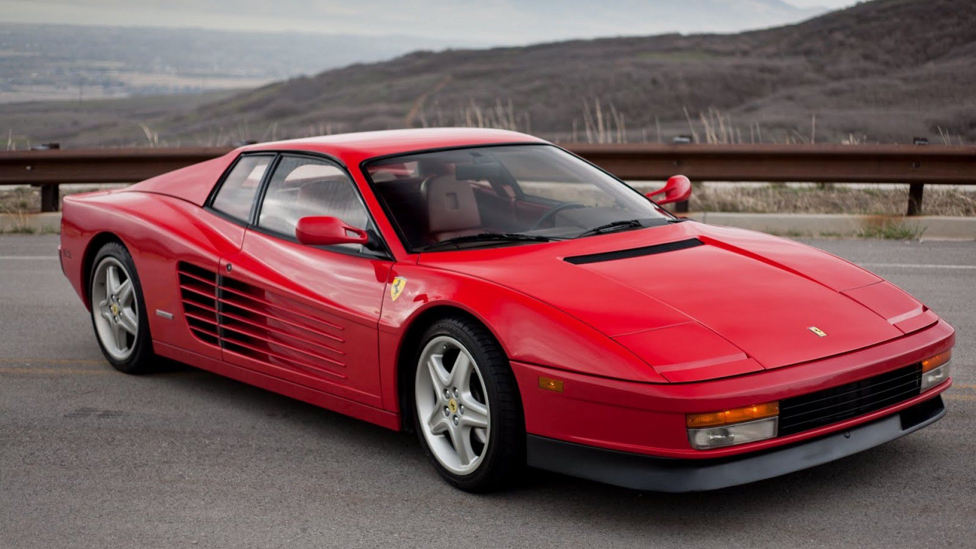 A red Ferrari Testarossa parked in a picturesque setting, showcasing its iconic design and timeless appeal.
