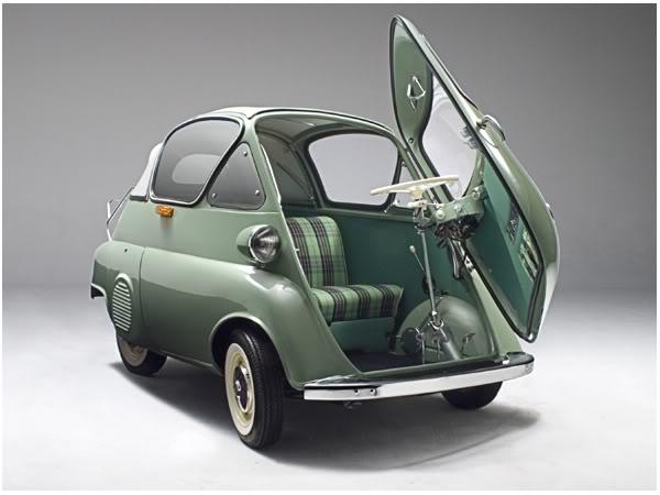 A vintage BMW Isetta microcar parked on a cobblestone street, its iconic bubble-shaped body and single front door visible, showcasing its compact size and unique design.